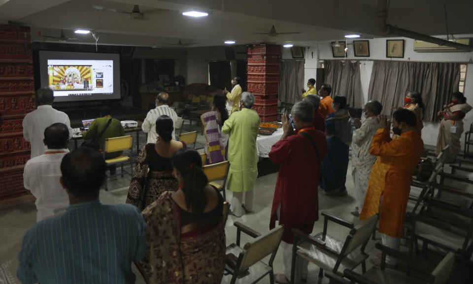 Members of the festival organizing team at the Kali Bari Hindu temple pray via live transmission on the first day of Durga Puja celebrations in New Delhi, India, Thursday, Oct. 22, 2020. Most of the festival festivities are being scaled down following the health officials warning about the potential for the coronavirus to spread during the religious festival season, which is marked by huge gatherings in temples and shopping districts. (AP Photo/Manish Swarup)