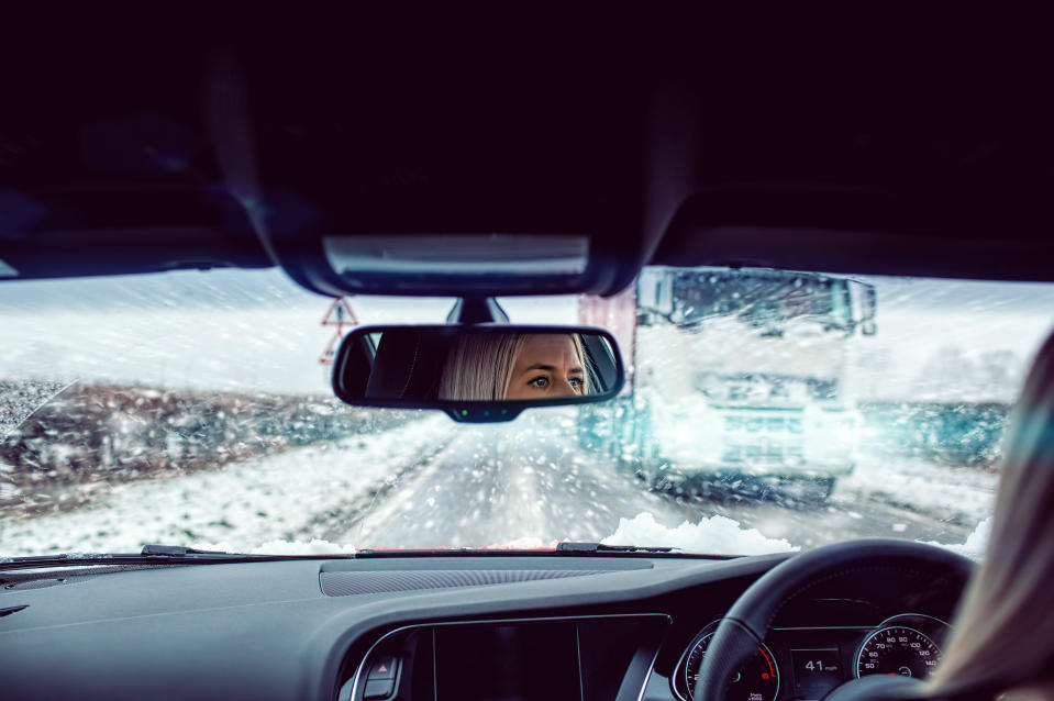 Woman driving car through winter blizzard on road in the UK.