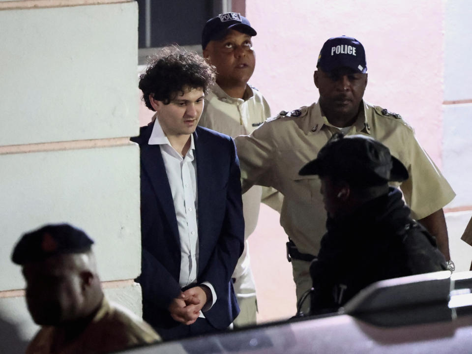 Sam Bankman-Fried, who founded and led FTX until a liquidity crunch forced the cryptocurrency exchange to declare bankruptcy, is escorted out of the Magistrate Court building after his arrest, in Nassau, Bahamas December 13, 2022. REUTERS/Dante Carrer