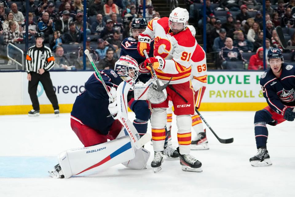 Oct 20, 2023; Columbus, Ohio, USA; Columbus Blue Jackets goaltender Spencer Martin (30) deflects a puck with pressure from Calgary Flames center Nazem Kadri (91) during the second period of the NHL hockey game at Nationwide Arena.