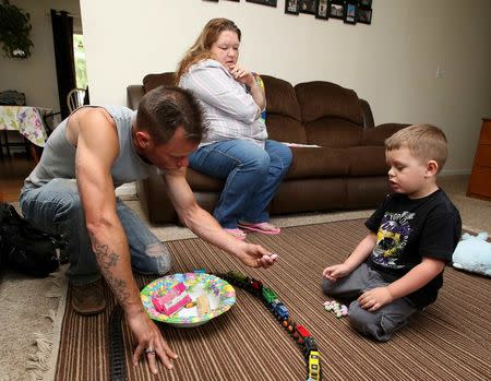 Joshua Sekerak (R) takes a break from playing with his trains to have a piece of candy with his dad Josh as his mom Jennifer looks on at their home in Leetonia, Ohio, United States on May 21, 2016. REUTERS/Aaron Josefczyk