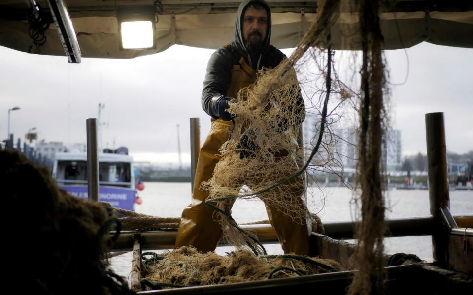 Fisherman Nicolas Bishop of the Jeremy-Florent II fishing boat cleans a net at the port of Boulogne-sur-Mer, northern France