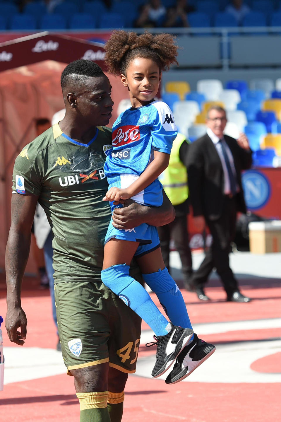 Brescia's Mario Balotelli holds his daughter Pia wearing a Napoli soccer team jersey, as he enters the pitch prior to the start of the Italian Serie A soccer match between Napoli and Brescia at the San Paolo stadium in Naples, Italy, Sunday, Sept. 29, 2019. (Cesare Abbate/ANSA Via AP)