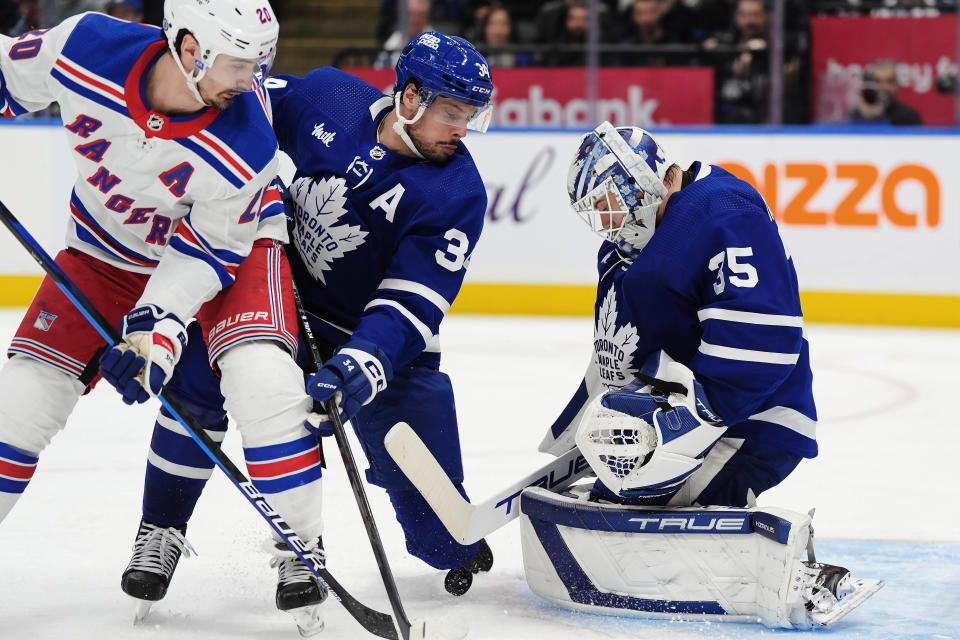 Toronto Maple Leafs goaltender Ilya Samsonov (35) makes a save as New York Rangers' Chris Kreider (20) and Maple Leafs' Auston Matthews (34) work next to him during the third period of an NHL hockey game Saturday, March 2, 2024, in Toronto. (Frank Gunn/The Canadian Press via AP)