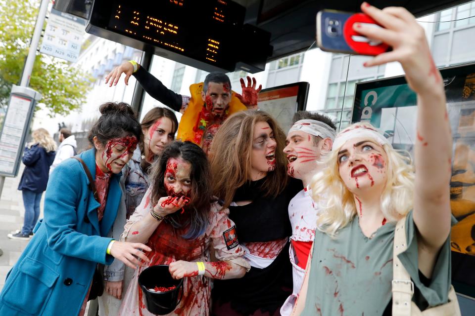 <p>People wearing costumes pose for photograph at a bus stop before participating in a zombie walk on World Zombie Day in London on Oct. 7, 2017. (Photo: Tolga Akmen/AFP/Getty Images) </p>