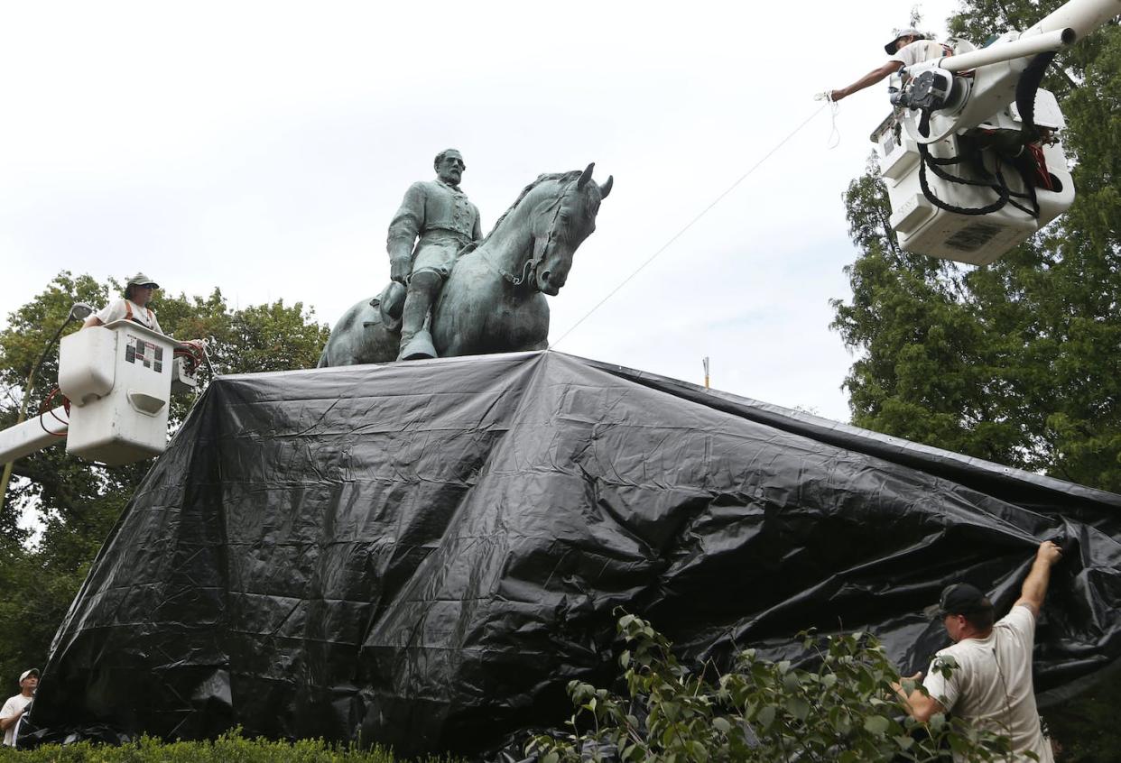 Charlottesville city workers drape a tarp over the statue of Confederate Gen. Robert E. Lee in 2018. Debate over removing the statue continues today. <a href="http://www.apimages.com/metadata/Index/Confederate-Monuments-Virginia/d95f1d175d4f4e1f94cdaec565c90845/3/0" rel="nofollow noopener" target="_blank" data-ylk="slk:AP Photo/Steve Helber, File;elm:context_link;itc:0;sec:content-canvas" class="link ">AP Photo/Steve Helber, File</a>