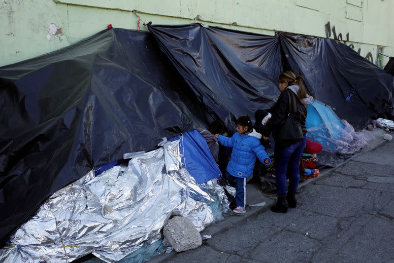 Mexican asylum seekers, who are camping near the Paso del Norte international border crossing bridge while waiting to apply for asylum to the U.S., gather outside their tents in Ciudad Juarez