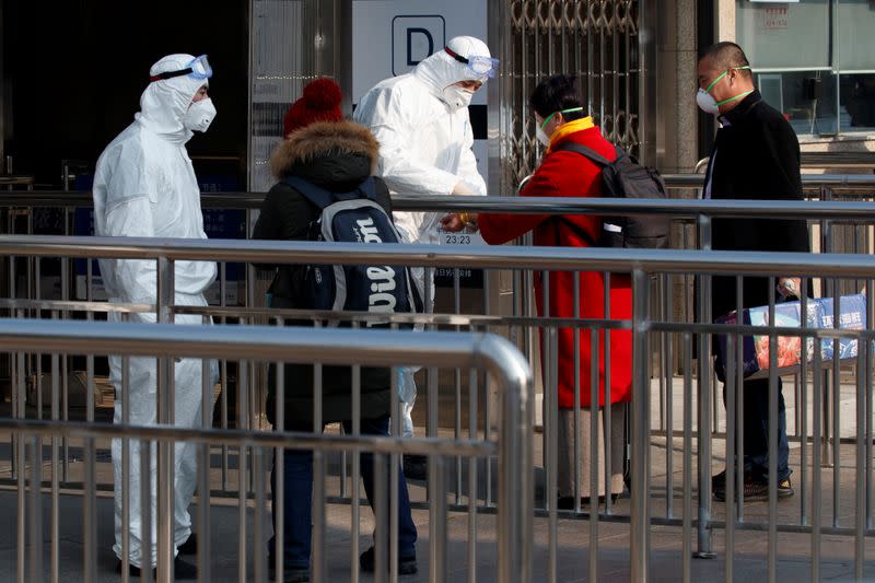 Workers take the body temperature of passengers before they enter the subway station outside the Beijing Railway Station in Beijing