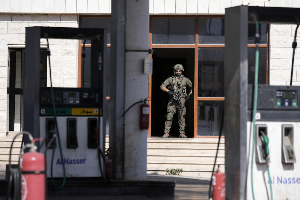 An Israeli soldier stands guard in a gas station during a search operation in the West Bank village of Qafin for the suspected gunmen who shot and killed an Israeli civilian near the entrance to a Jewish settlement of Hermesh, Tuesday, May 30, 2023. (AP Photo/Majdi Mohammed)