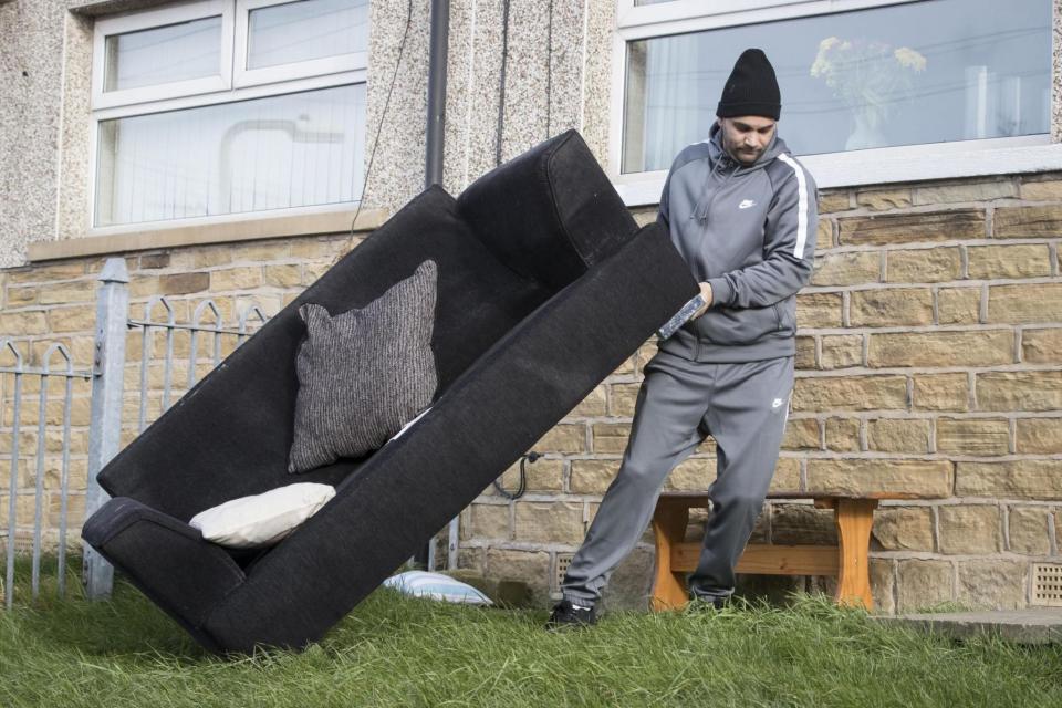 All change: A neighbour helps remove a sofa from the home of Beverley Doran (PA)