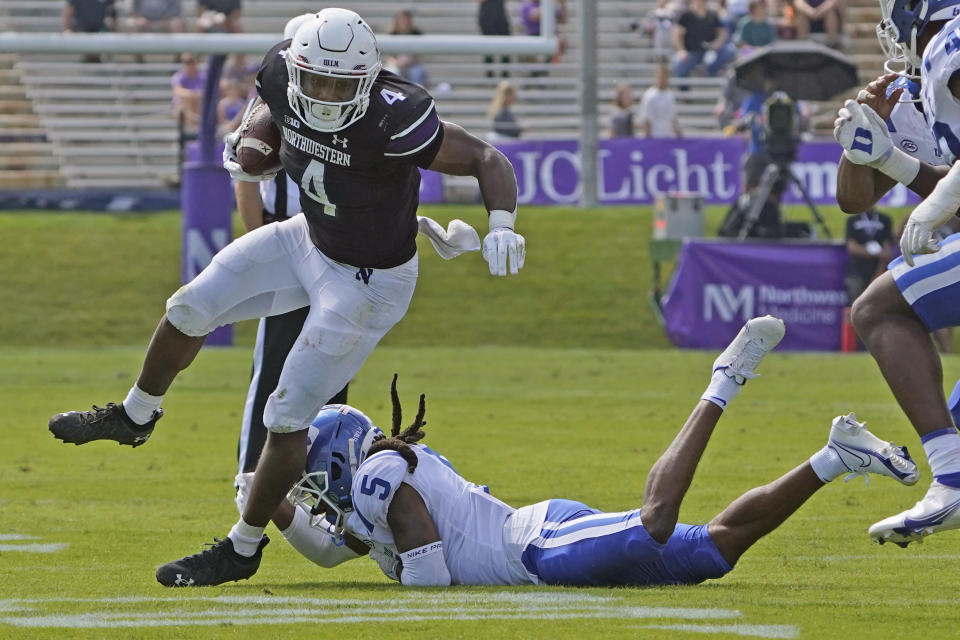 Northwestern running back Cam Porter (4) runs past Duke defensive back Datrone Young (5) during the first half of an NCAA college football game, Saturday, Sept.10, 2022, in Evanston, Ill. (AP Photo/David Banks)