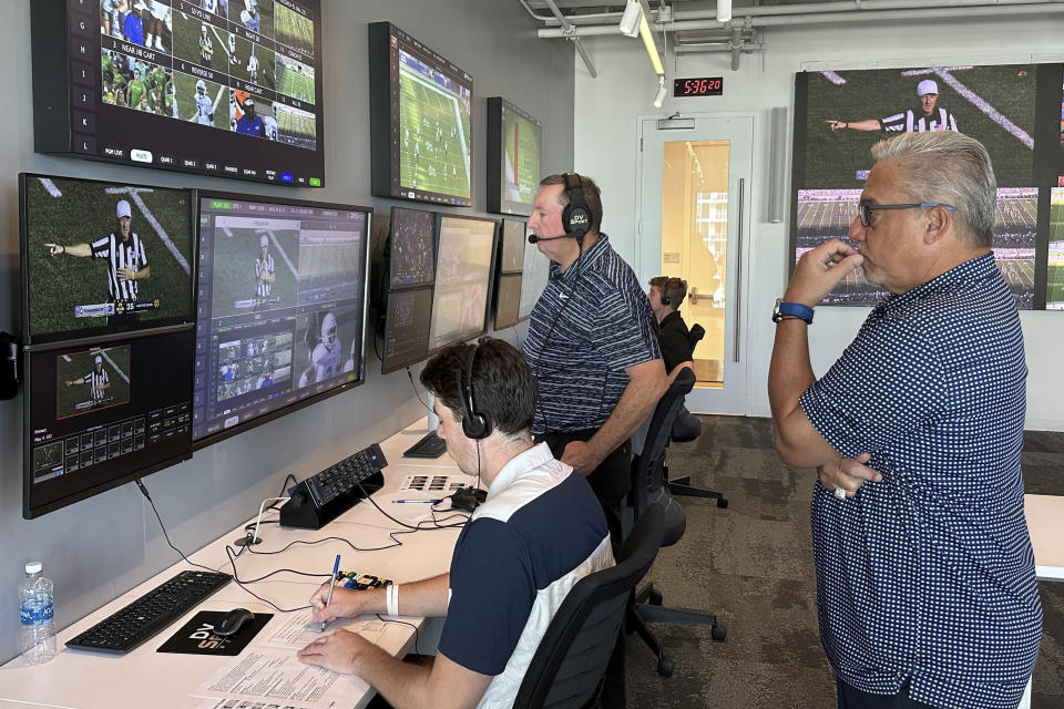 Alberto Riveron, right, the Atlantic Coast Conference supervisor of football officials, works in the league’s new gameday operations center, Saturday, Sept. 2, 2023, in Charlotte, N.C. The tech-heavy gameday center — roughly four times larger than the previous setup — is in the league's new headquarters, located in a downtown tower overlooking the stadium home of the NFL's Carolina Panthers. (AP Photo/Aaron Beard)