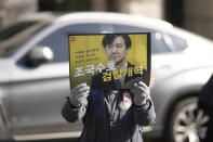 A supporter of former Justice Minister Cho Kuk holds a sign with a picture of Cho Kuk outside of the Seoul Central District Court in Seoul, South Korea, Friday, Feb. 3, 2023. The court on Friday sentenced Cho to two years in prison, after he was found guilty of creating fake credentials to help his children get into prestigious schools, a scandal that rocked the country’s previous government and sparked huge protests. The letters read "Reform the Prosecution," and "Protect Cho Kuk." (AP Photo/Lee Jin-man)