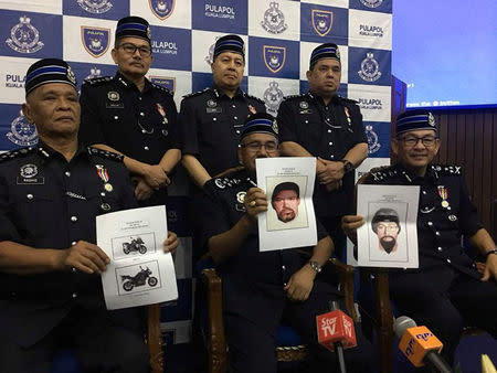 A Royal Malaysia Police handout shows police officers holding computer generated mugshots of the two men suspected of gunning down a Palestinian man at a news conference in Kuala Lumpur released April 23, 2018. Royal Malaysia Police/Handout via REUTERS