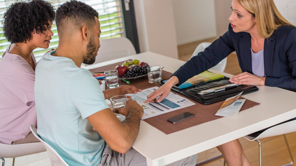 Female financial advisor discussing with young couple at home.