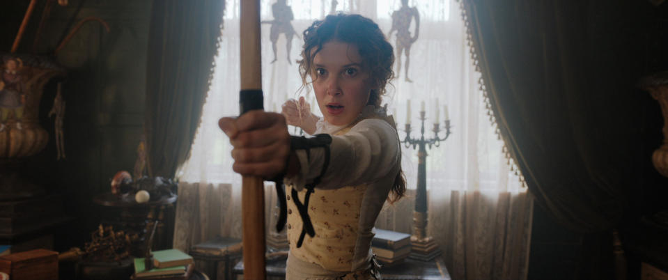 Millie Bobby Brown's Enola Holmes holds a bow and arrow