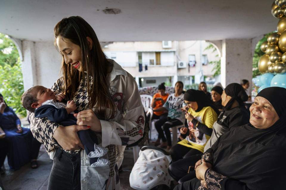 Amar Watad holds her 13-day-old son, Nidal, during a birth celebration for the Arab family at the entrance to her apartment building as her mother-in-law Zakya Watad, right, looks on in the mixed Arab-Jewish town of Lod, central Israel, Wednesday, May 26, 2021. About a third of the city's population are Arabs, many of them descendants of Palestinians who formed the majority of the city before a mass expulsion amid the 1948 war around Israel's creation. (AP Photo/David Goldman)