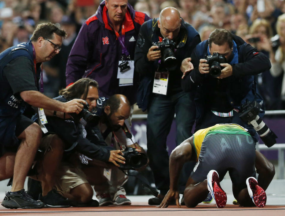 News photographers crowd around Jamaica's Usain Bolt as he celebrates victory after the men's 100m final during the London 2012 Olympic Games at the Olympic Stadium August 5, 2012. REUTERS/Mark Blinch (BRITAIN - Tags: OLYMPICS SPORT ATHLETICS) 