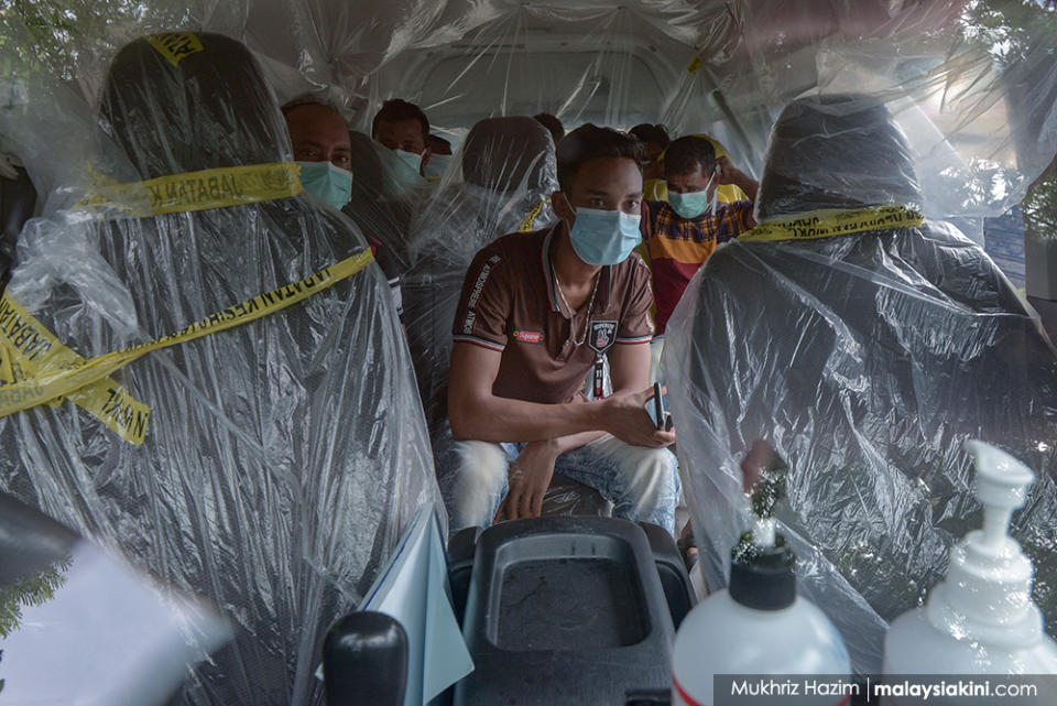 Foreign workers sit in a Health Ministry van covered with plastic as they make their way to the hospital for Covid-19 screening in Kampung Baru on Apr 14, 2020.