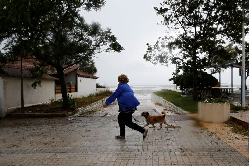 A woman walks her dog near the sea in the village of Gastouni, as a rare storm, known as a Medicane (Mediterranean hurricane), hit western Greece