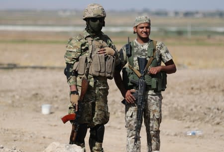 Turkey-backed Syrian rebel fighters stand together as they hold their weapons near the border town of Tel Abyad