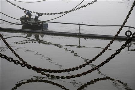 Men work on a boat on the river Clyde during a misty morning in Glasgow, Scotland January 14, 2014. REUTERS/Stefan Wermuth