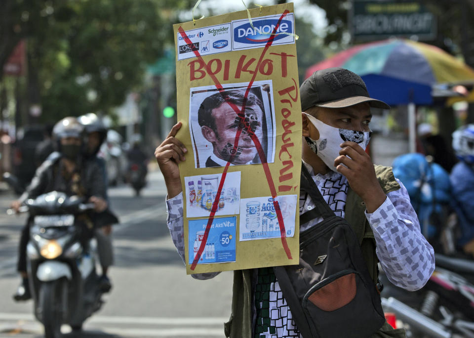 A Muslim man holds a defaced poster of French President Emmanuel Macron during a protest at Al Jihad mosque in Medan, North Sumatra, Indonesia, Friday, Oct. 30, 2020. Muslims around the world have been calling for both protests and a boycott of French goods in response to France's stance on caricatures of Islam's most revered prophet. (AP Photo/Binsar Bakkara)