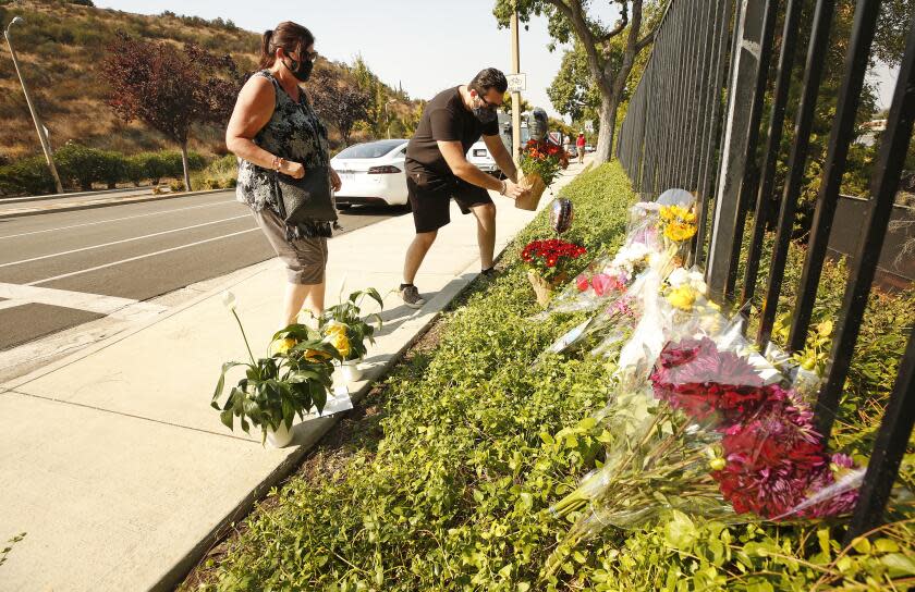 WESTLAKE VILLAGE, CA - SEPTEMBER 30: Lorraine Maralian and her son Anthony Maralian of Westlake Village place flowers and pray at a growing memorial for two brothers who were fatally injured while crossing Triunfo Canyon Road at Saddle Mountain Drive in their Westlake Village neighborhood with their family at 7:10 pm Tuesday evening. Rebecca Grossman, 57, a co-founder of the Grossman Burn Foundation was arrested on two counts of vehicular manslaughter in the death of the two juvenile pedestrians that were in the crosswalk and is being held on $2 million bail. Westlake Village on Wednesday, Sept. 30, 2020 in Westlake Village, CA. (Al Seib / Los Angeles Times