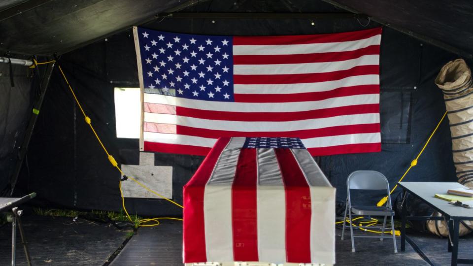 A transfer case draped in the American flag sits in a tent at the theatre mortuary evacuation point where the simulated remains of a fallen Soldier are prepped for departure back home during the 2015 Mortuary Affairs Exercise at Fort Pickett, Va., May 29, 2015. (U.S. Army photo by Brian Godette/Released)