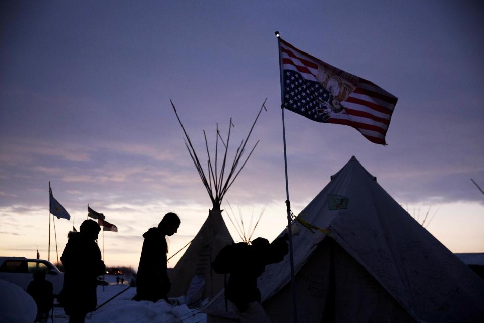 FILE - In this Dec. 2, 2016, file photo, travelers arrive at the Oceti Sakowin camp where people have gathered to protest the Dakota Access oil pipeline as they walk into a tent next to an upside-down american flag in Cannon Ball, N.D. Some Native Americans worry the transition to a Donald Trump administration signals an end to eight years of sweeping Indian Country policy reforms. But Trump's Native American supporters said they're hopeful he will cut through some of the government red tape that they believe has stifled economic progress on reservations. (AP Photo/David Goldman, File)