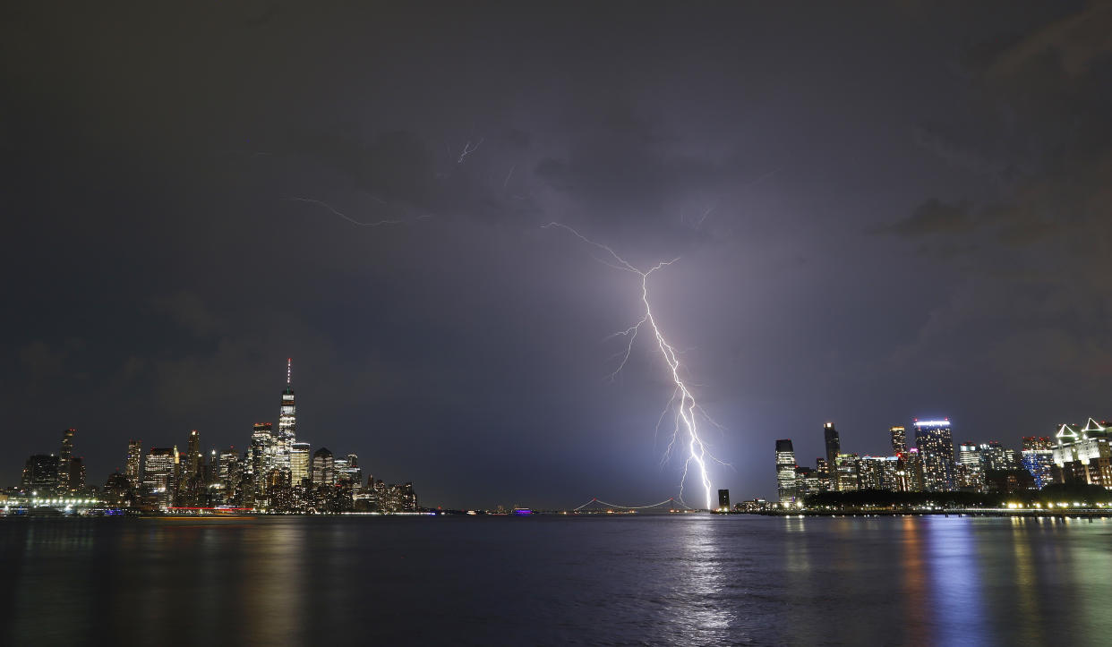 A lightning bolt strikes near New York City, with the lighted Manhattan skyline, the Hudson River and Jersey City on display in this night scene.