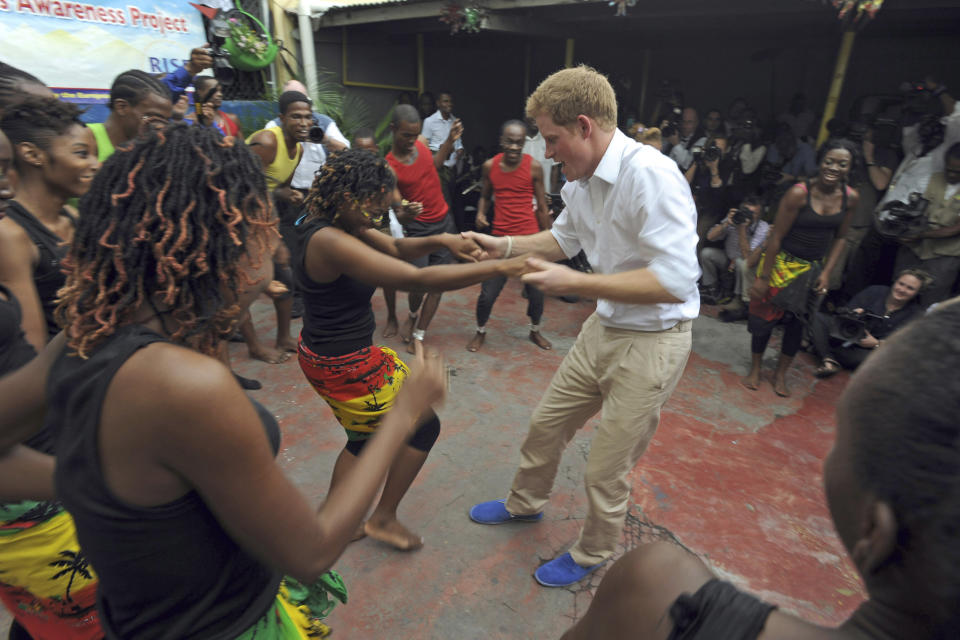 FILE - In this Tuesday, March 6, 2012 file photo, Britain's Prince Harry dances with a girl during a visit to the non-governmental organization RISE (Reaching Individuals through Skills and Education) in Kingston, Jamaica. Princess Diana’s little boy, the devil-may-care red-haired prince with the charming smile is about to become a father. The arrival of the first child for Prince Harry and his wife Meghan will complete the transformation of Harry from troubled teen to family man, from source of concern to source of national pride. (AP Photo/Collin Reid, File)