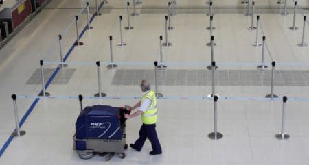 FILE PHOTO: An airport worker cleans around empty check-in desks in a terminal in Manchester Airport, in Manchester, northern England April 16, 2010. REUTERS/Phil Noble/File Photo