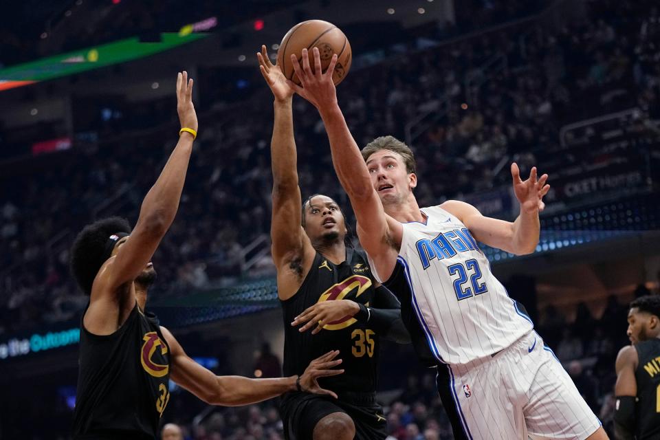 Orlando Magic forward Franz Wagner (22) shoots in front of Cleveland Cavaliers center Jarrett Allen (31) and forward Isaac Okoro (35) during the first half of an NBA basketball game Wednesday, Dec. 6, 2023, in Cleveland. (AP Photo/Sue Ogrocki)