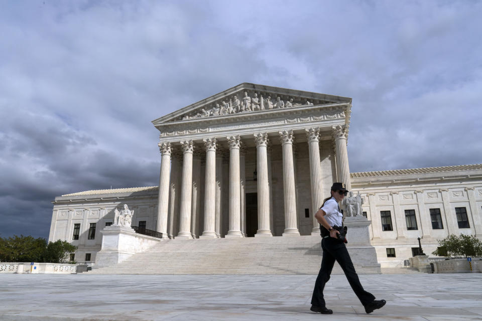 A U.S. Supreme Court police officer walks by during a voting rights rally, at the Supreme Court Oct. 28, 2021, in Washington. Supreme Court police officers are looking for a few good men and women — as are law enforcement departments around the country in a tight employment market. High court personnel are showing up on college campuses, military bases and other venues to try to fill some of the force's many vacancies.(AP Photo/Jose Luis Magana, File)