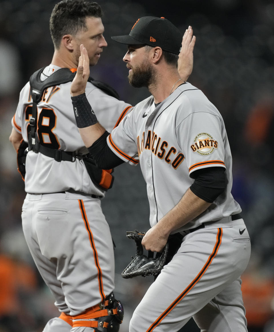 San Francisco Giants first baseman Brandon Belt, front, is congratulated by catcher Buster Posey after the ninth inning of a baseball game against the Colorado Rockies Saturday, Sept. 25, 2021, in Denver. The Giants won 7-2. (AP Photo/David Zalubowski)