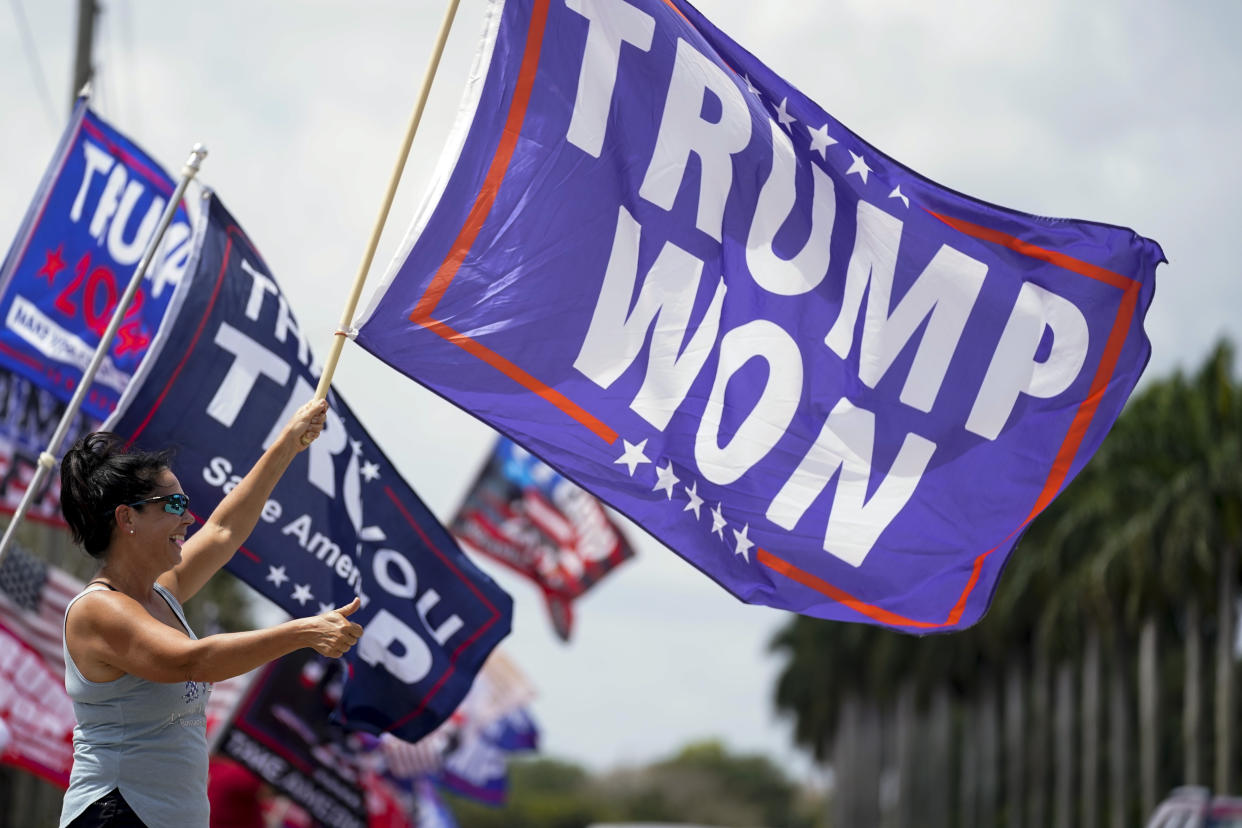 FILE - Supporters of former President Donald Trump wave flags in support of Trump outside Trump International Golf Club, Saturday, April 1, 2023, in West Palm Beach, Fla. (AP Photo/Evan Vucci, File)