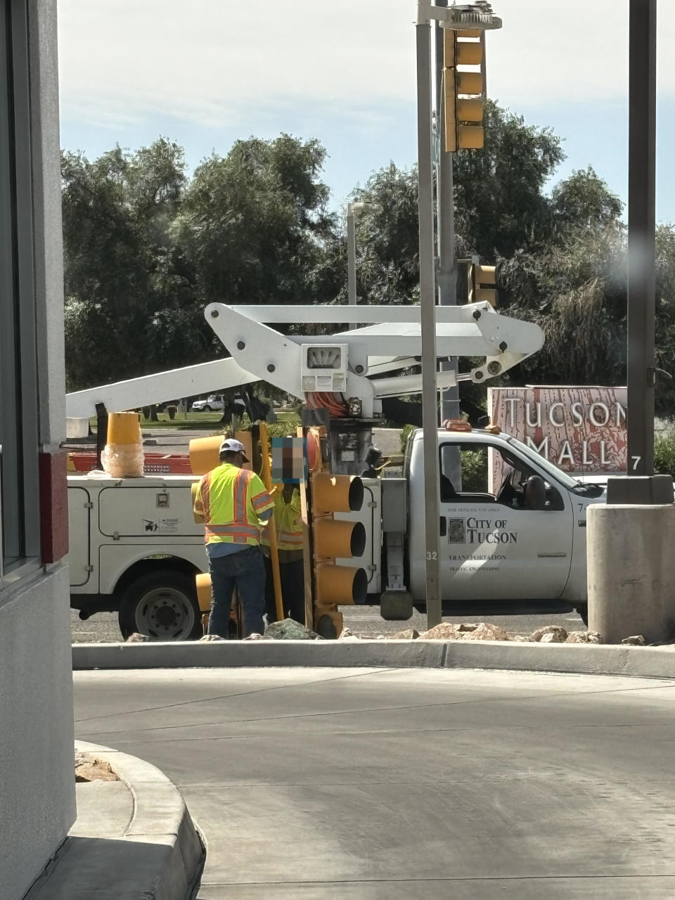 Two workers in safety vests operating a cherry picker near a "City of Tucson" truck