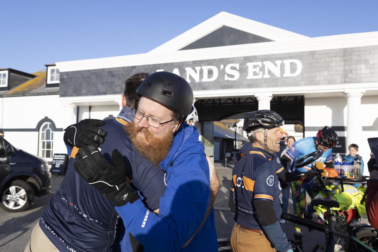 Members of the team embrace after arriving at Land's End. 