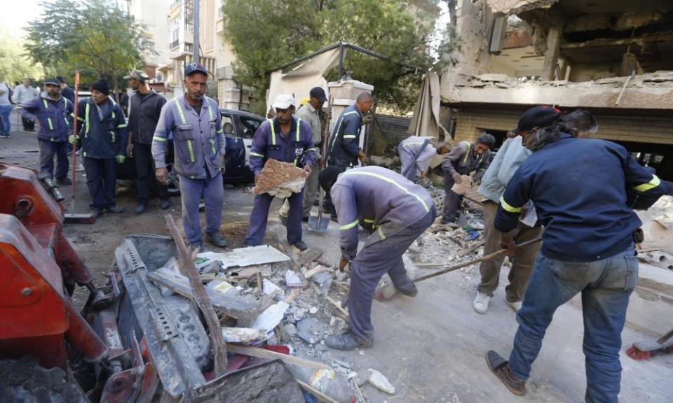 Syrian municipality workers clear debris from a building in the Mazze neighbourhood after the airstrike.