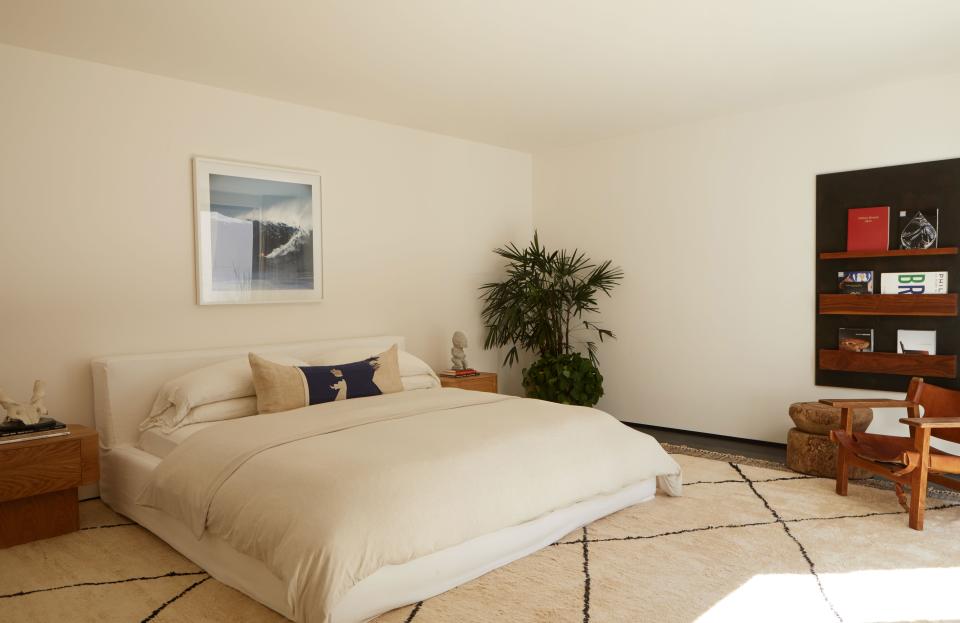 The bed—with a white linen slipcover from James Perse—is placed on a Moroccan rug from Woven Accents. The photograph is by LeRoy Grannis, the Maker’s Book Rack is from Lawson Fenning, and the Spanish chair is by Børge Mogensen.