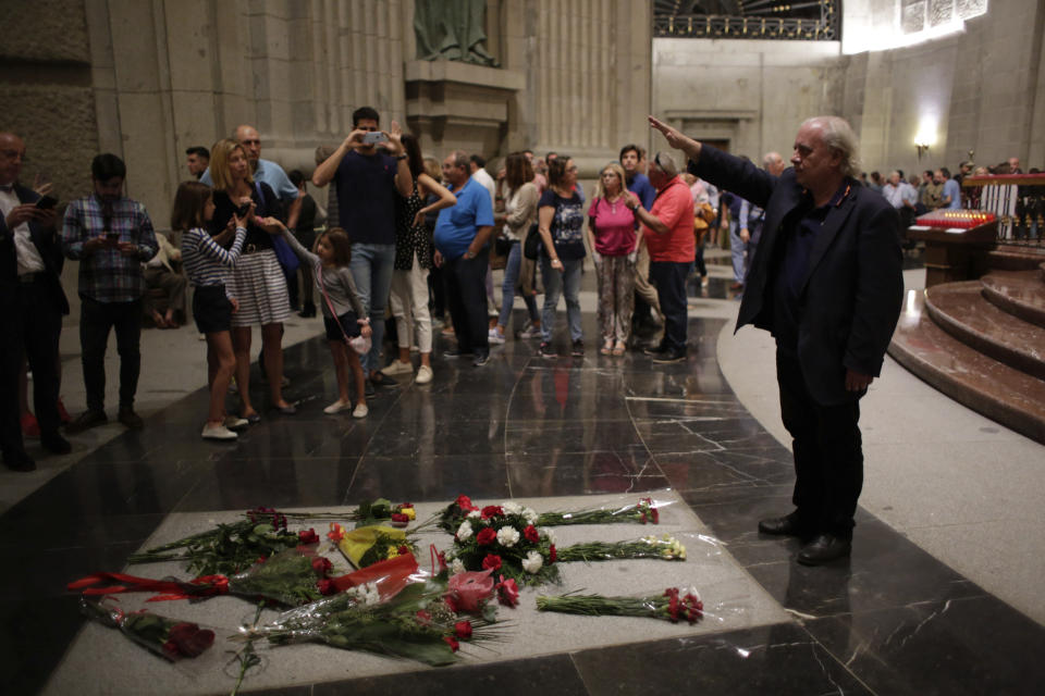 In this Saturday, Oct. 5, 2019 photo, a man makes the fascist salute at the tomb of Jose Antonio Primo de Rivera, the founder of the Spanish right-wing movement La Falange, inside the basilica at the Valley of the Fallen monument near El Escorial, outside Madrid. After a tortuous judicial and public relations battle, Spain's Socialist government has announced that Gen. Francisco Franco's embalmed body will be relocated from a controversial shrine to a small public cemetery where the former dictator's remains will lie along his deceased wife. (AP Photo/Alfonso Ruiz)