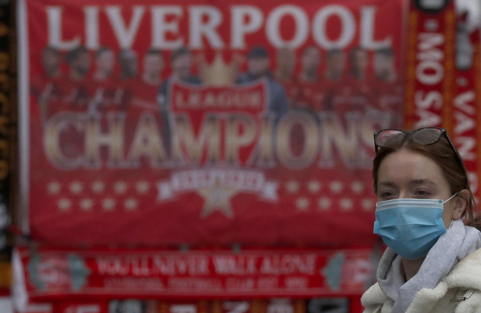 A woman wears a face covering on a shopping street as new measures across the region are set to come into force in Liverpool, England, Wednesday, Oct. 14, 2020. New plans unveiled this week show Liverpool is in the highest-risk category, and its pubs, gyms and betting shops have been shut.(AP Photo/Frank Augstein)