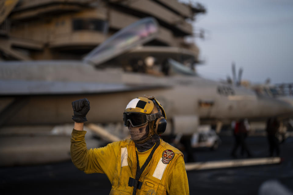 Un agente de movilidad de aeronaves da instrucciones a un avión en la pista en la cubierta del portaaviones USS Dwight D. Eisenhower, en el Mar Rojo, el martes 11 de junio de 2024. (AP Foto/Bernat Armangue)