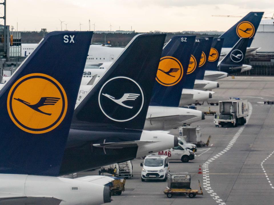 Blue tails of Lufthansa aircraft with the company's logo, an encircled stylized crane in flight over a yellow background.