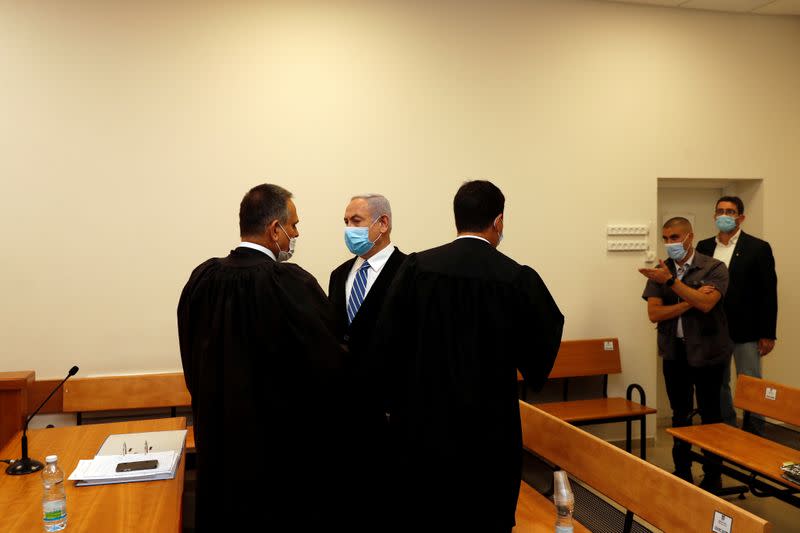 Israeli Prime Minister Benjamin Netanyahu, wearing a face mask, stands inside the court room as his corruption trial opens at the Jerusalem District Court