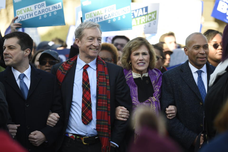 Democratic presidential contenders, from left, Pete Buttigieg, Tom Steyer, Deval Patrick and Steyer's wife Kat Taylor, second from right, link arms during a Martin Luther King Jr. march on Monday, Jan. 20, 2020, in Columbia, S.C. (AP Photo/Meg Kinnard)