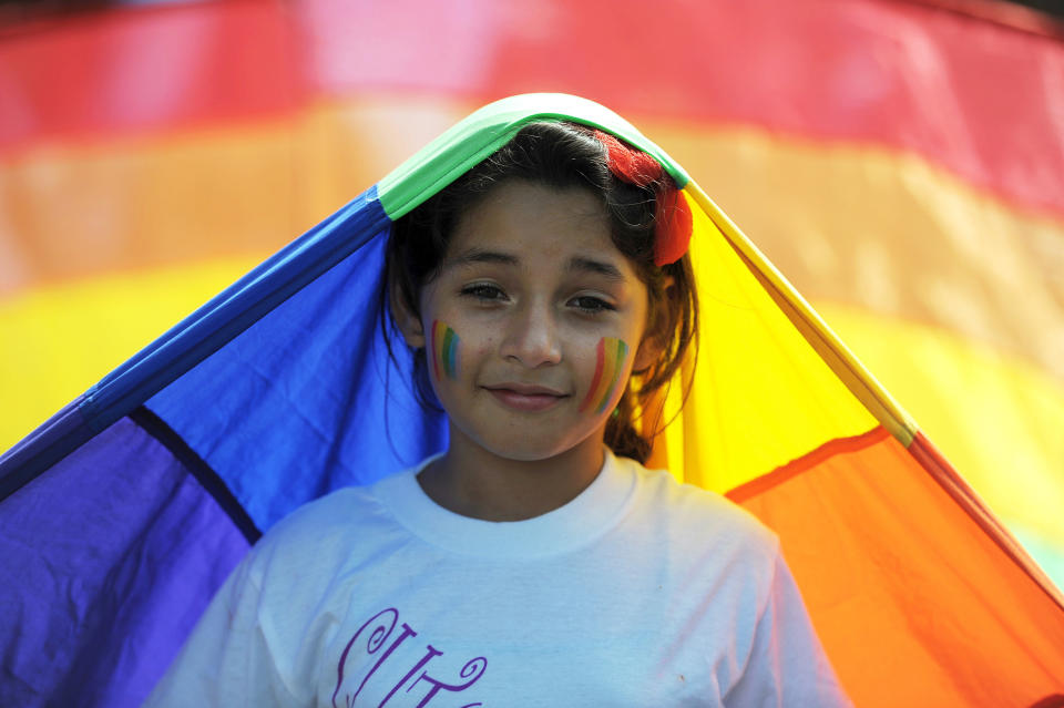 A young girl smiles during a Gay Pride parade along Roosevelt Avenue in San Salvador on June 29, 2013. AFP PHOTO/Jose CABEZAS