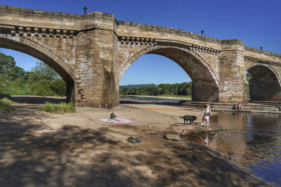 A family play in the shallows on the banks of the river Tyne, that has very low water levels, at Corbridge, England, Monday June 1, 2020. Families who are locked down because of the coronavirus have been able to visit local beauty spots as warm weather has swept the region. (Owen Humphreys/PA via AP)