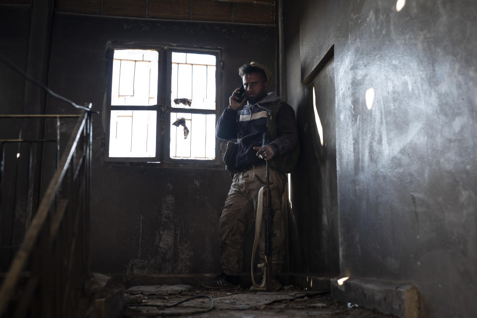 A U.S.-backed Syrian Democratic Forces (SDF) fighter talks on his phone inside a building used as a temporary base near the last land still held by Islamic State militants in Baghouz, Syria, Monday, Feb. 18, 2019. Hundreds of Islamic State militants are surrounded in a tiny area in eastern Syria are refusing to surrender and are trying to negotiate an exit, Syrian activists and a person close to the negotiations said Monday. (AP Photo/Felipe Dana)